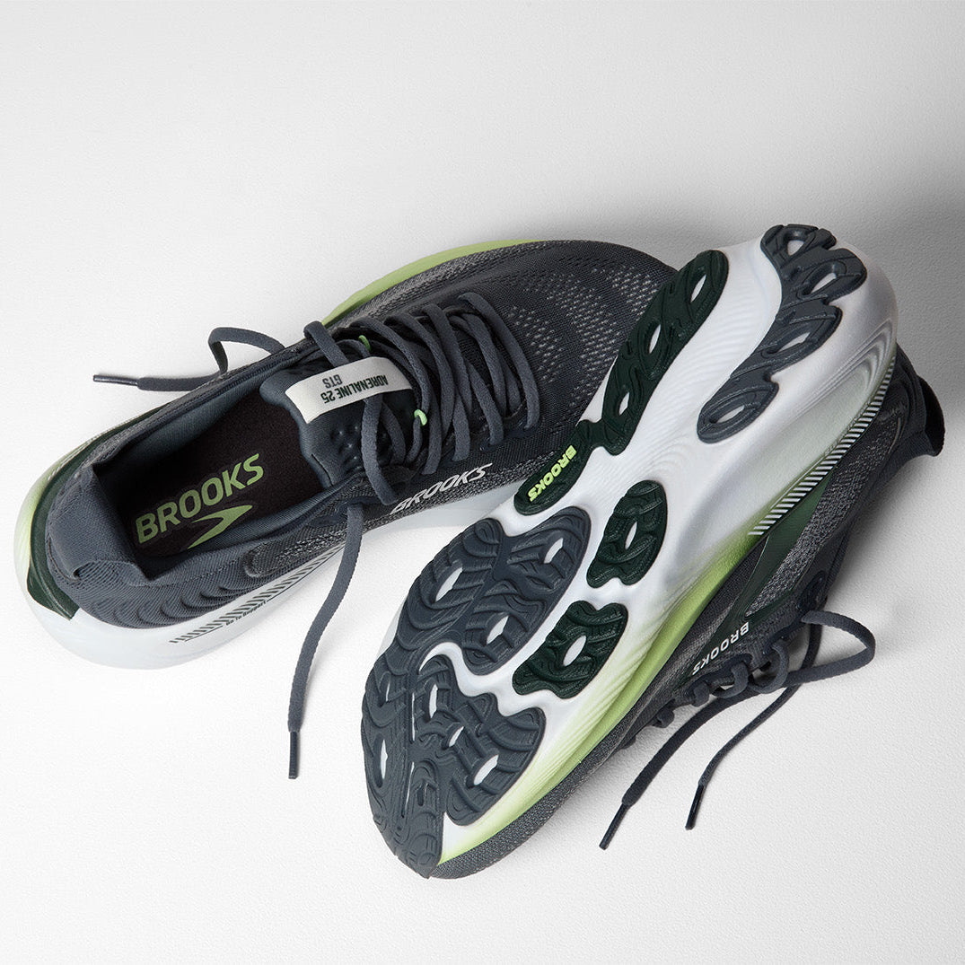 Black and white running shoes with green accents on a light gray background