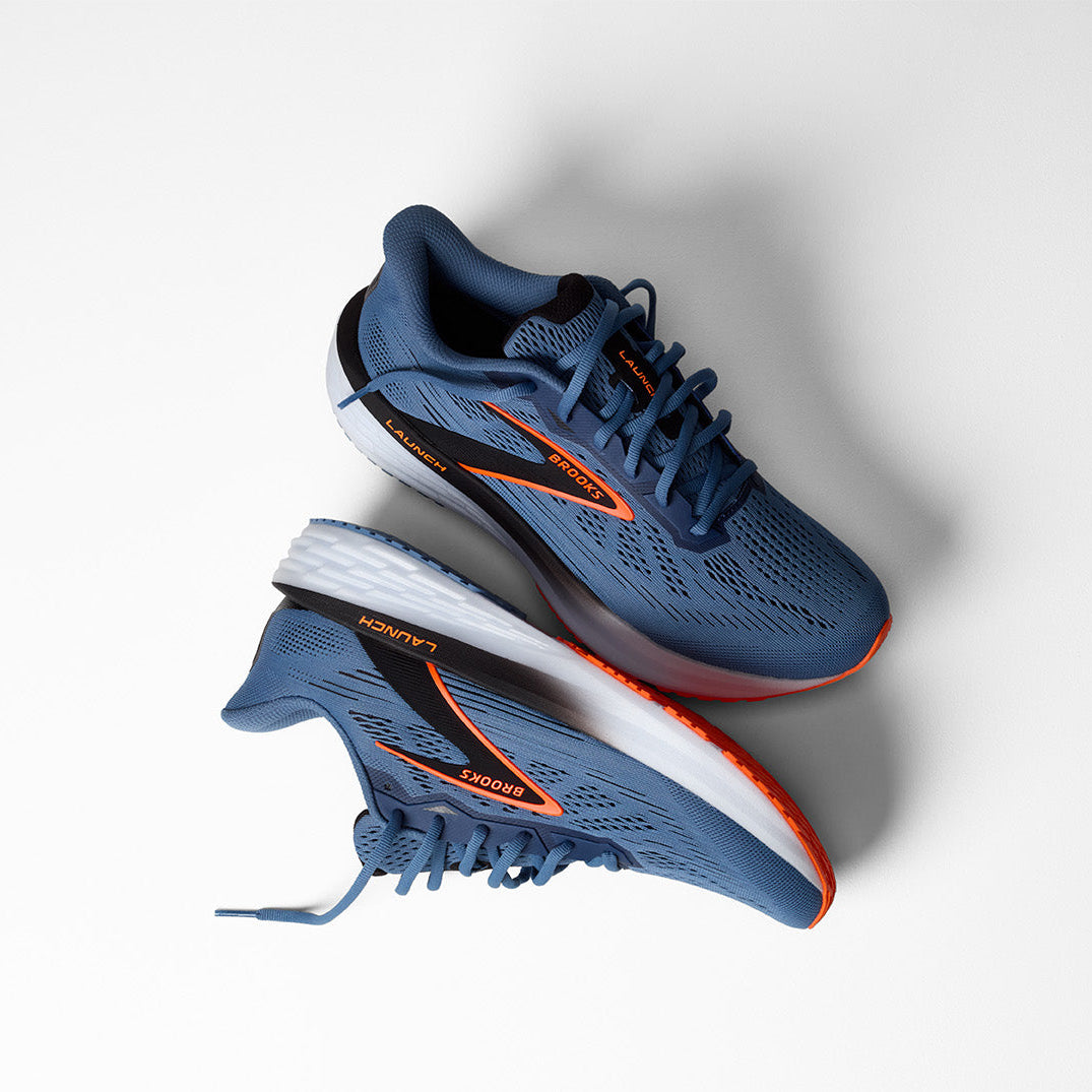 Pair of blue running shoes with orange accents on a white background