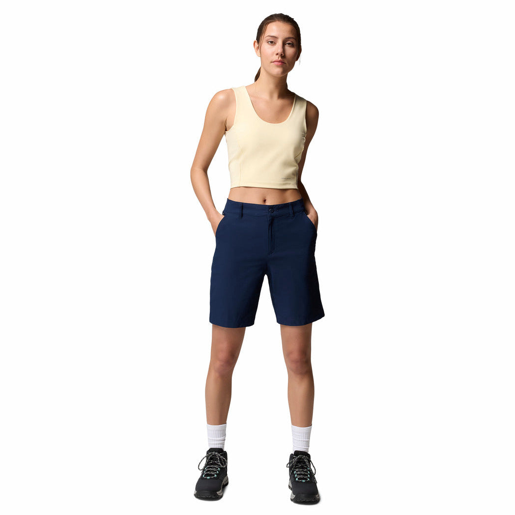 Woman wearing a beige tank top and navy shorts on a white background