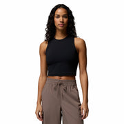 Woman wearing a black sleeveless top and brown pants on a white background