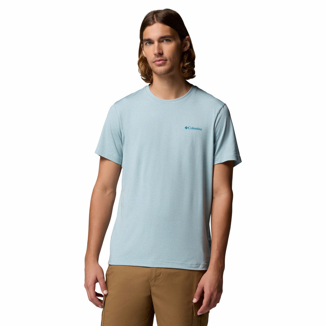 Man wearing a light blue t-shirt with a brand logo on a white background