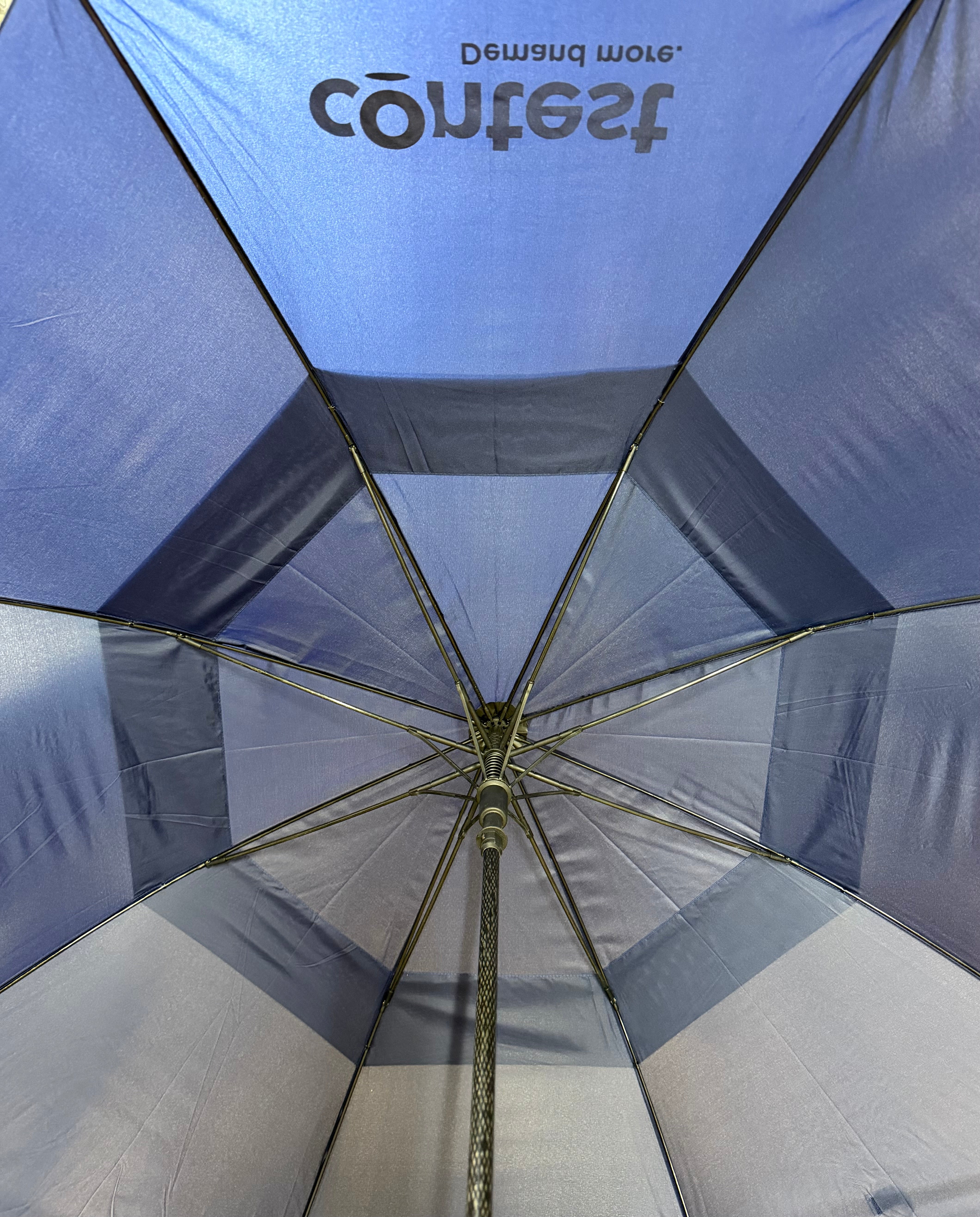 The underside of a blue and gray striped umbrella, viewed from below. The brand name 'Contest' is printed in gray on the top blue panel.