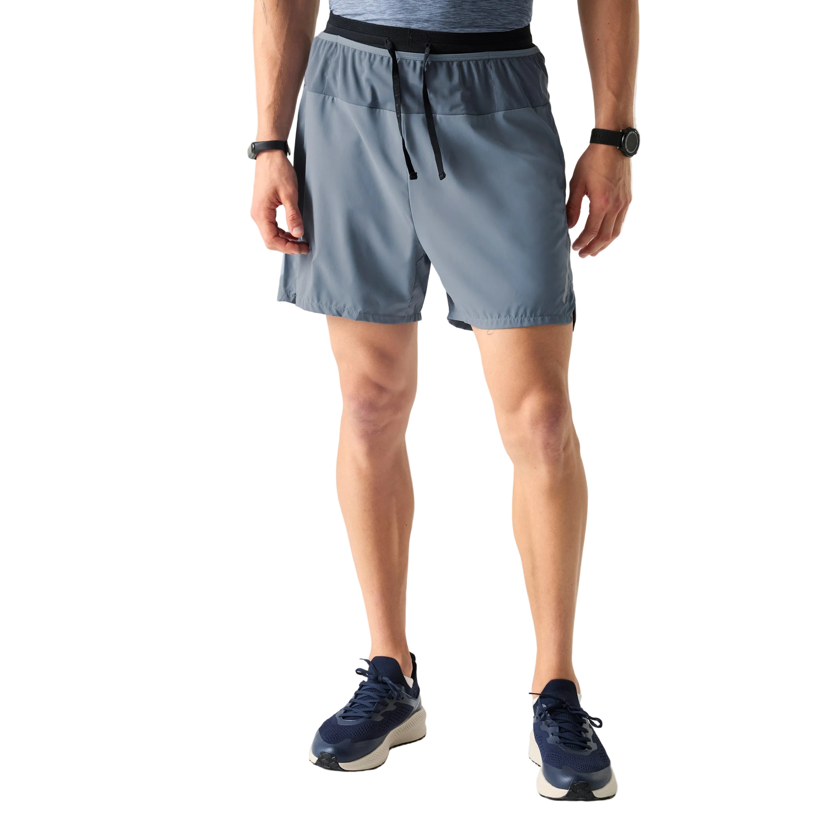 Person wearing light blue athletic shorts and dark blue sneakers on a plain background