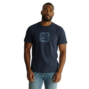 Man wearing a navy t-shirt with a logo and light blue jeans on a white background