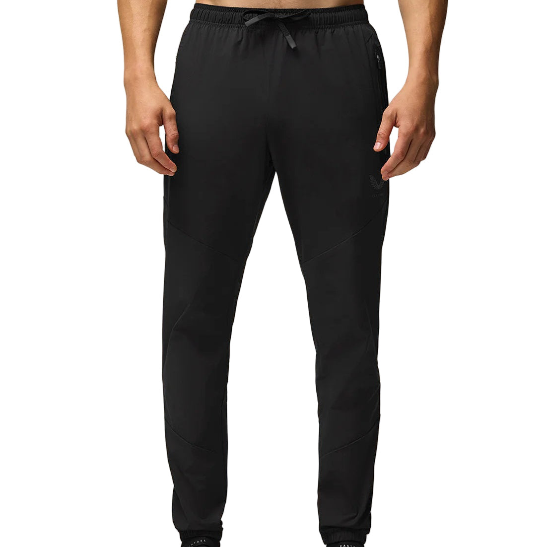 Person wearing black jogger pants on a beige background
