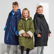 Three children wearing colorful ponchos against a white background